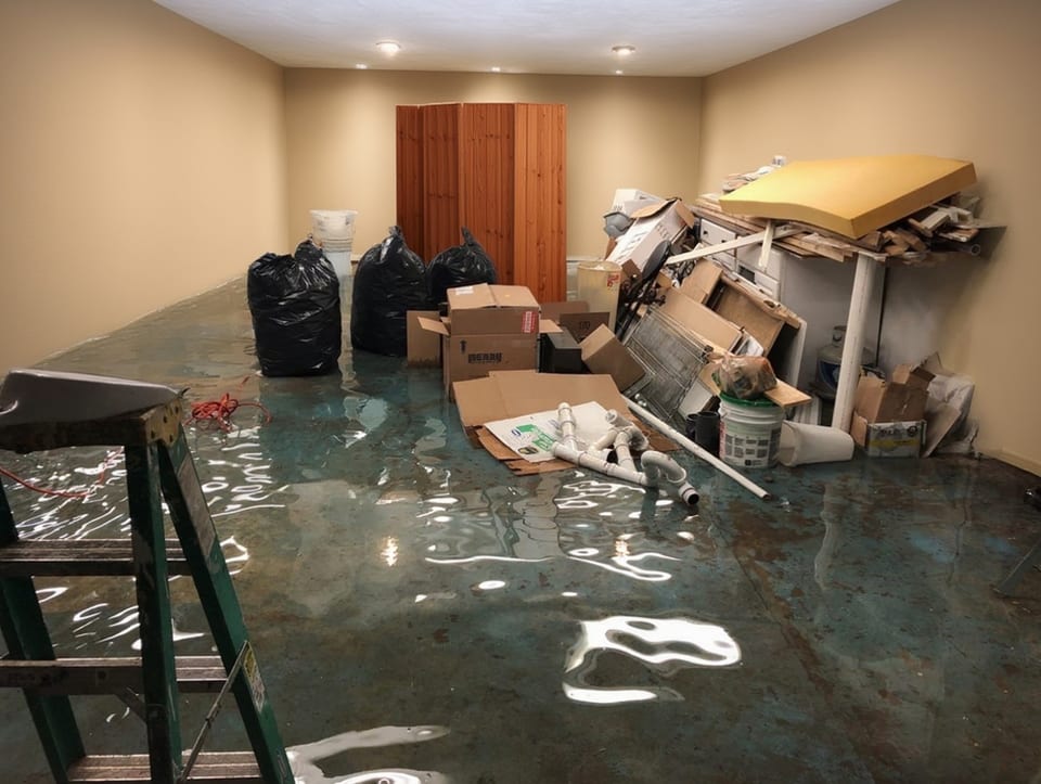 flooded basement with standing water covering the floor and waterlogged stored belongings