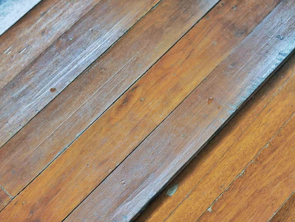 water-stained hardwood floor boards with visible grain and moisture damage along the plank edges